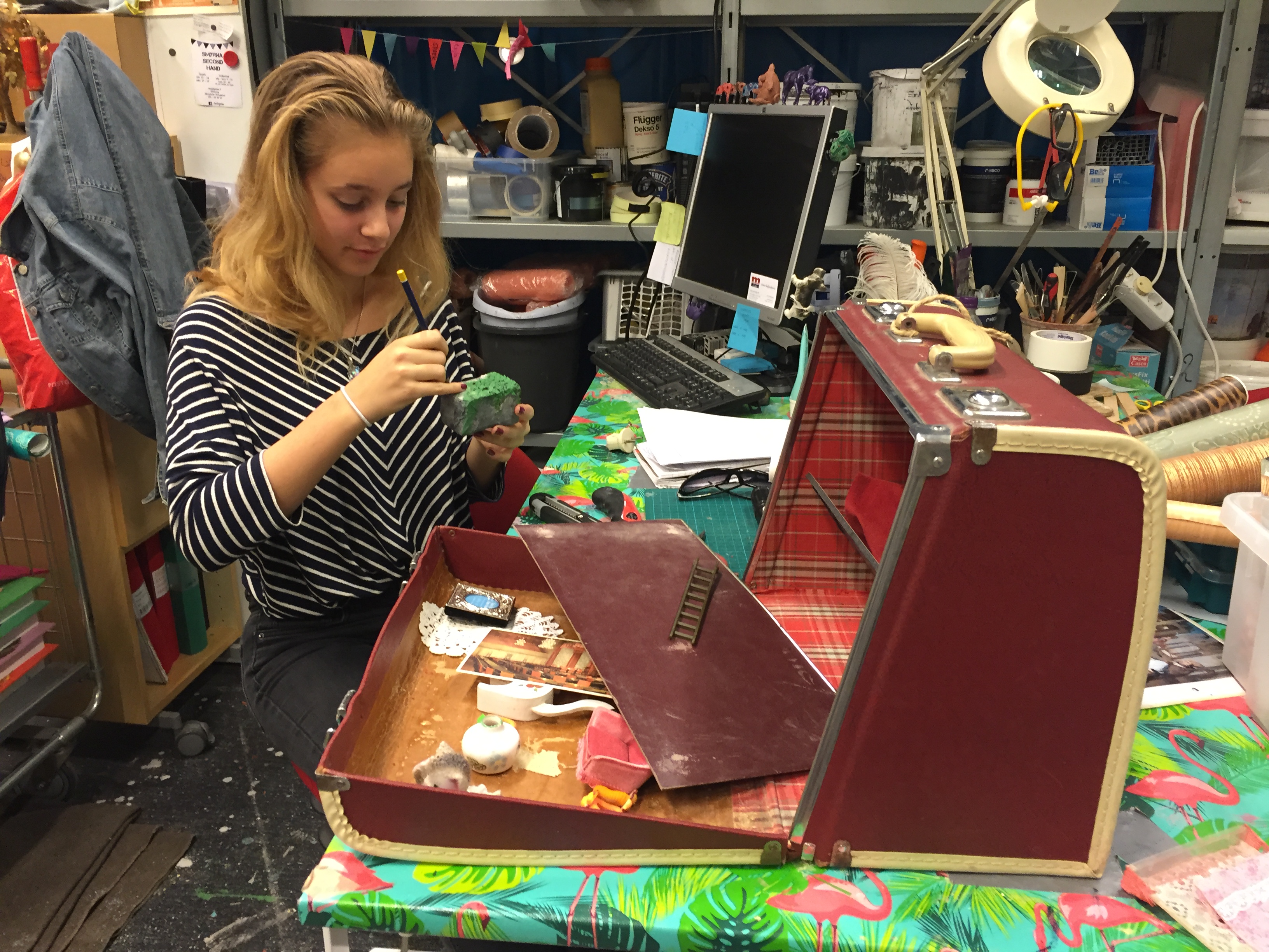Bild på Jasmine i rekvisitaverkstan. Hon gör en sten av frigolit.