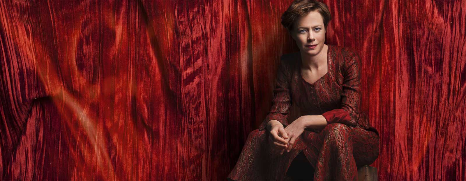  Mia Höglund- Melin klädd i röd klänning, mot en röd sammetsridå